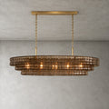 Smoky brown glass tiers on a Clérachic chandelier held by a gold long canopy bar, shown lit against a grey wall.