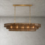 Smoky brown glass tiers on a Clérachic chandelier held by a gold long canopy bar, shown lit against a grey wall.