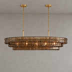 A smoke-brown Clérachic chandelier with two gold round canopies and slim stems, softly lit against a grey wall.