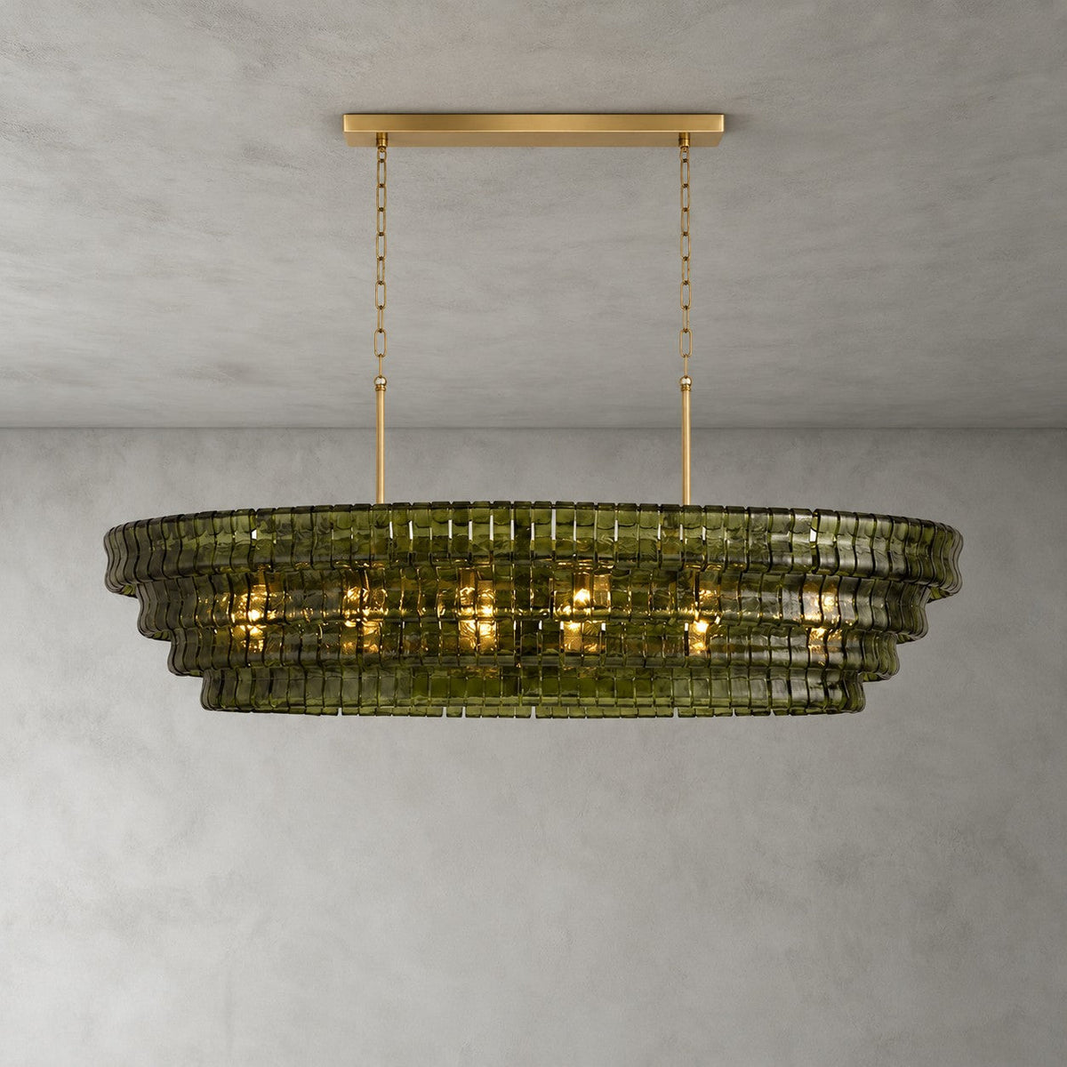 A four-tier green-glass Clérachic chandelier with a gold long canopy bar, shown from slightly below on a grey backdrop.