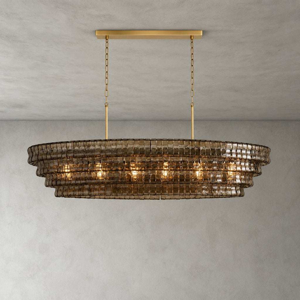 Four tiers of smoked glass on this Clérachic chandelier, with a gold long canopy bar and chain, against a grey wall.