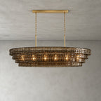 Four tiers of smoked glass on this Clérachic chandelier, with a gold long canopy bar and chain, against a grey wall.