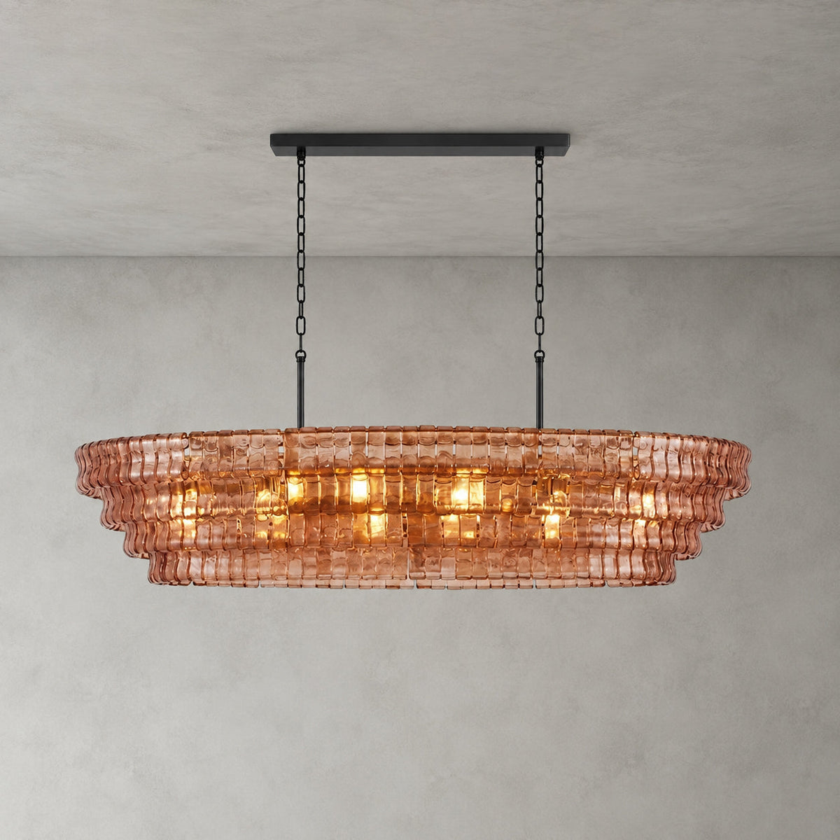 This Clérachic chandelier in rose-pink glass has four stepped tiers and a black long canopy bar, lit on a grey wall.