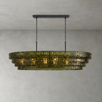 A green-glass Clérachic chandelier with four stepped tiers and a black long canopy bar, glowing on a grey wall.