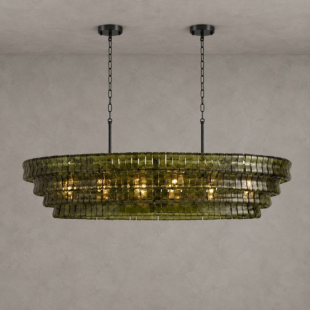 This Clérachic chandelier in green glass hangs from two black round canopies, its four tiers lit against grey.