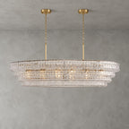 Clear glass on a four-tier Clérachic chandelier with two gold round canopies and slim stems, lit on a grey wall.
