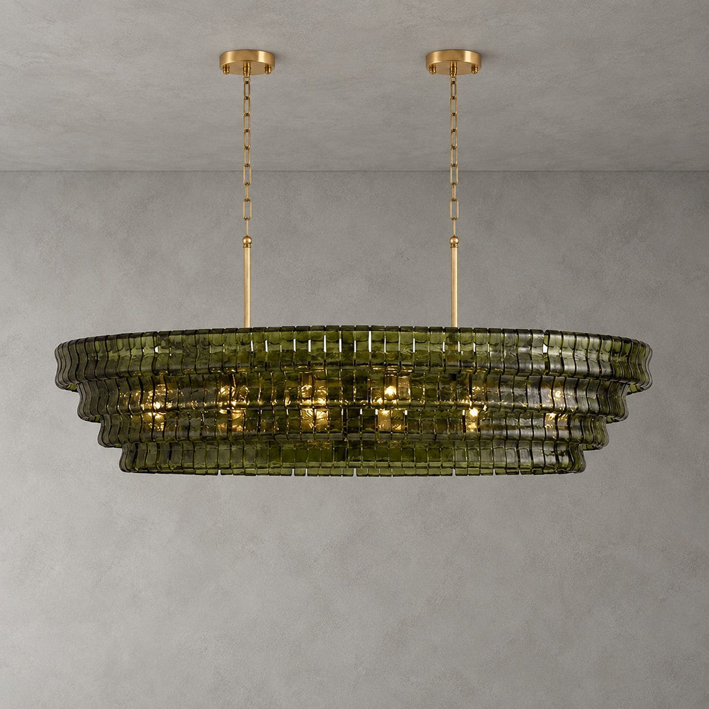 Four green-glass tiers on this Clérachic chandelier with two gold round canopies, glowing warmly on a grey wall.