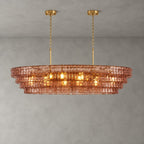 Rose-pink glass tiers of this Clérachic chandelier, with two gold round canopies and chain, lit against grey.