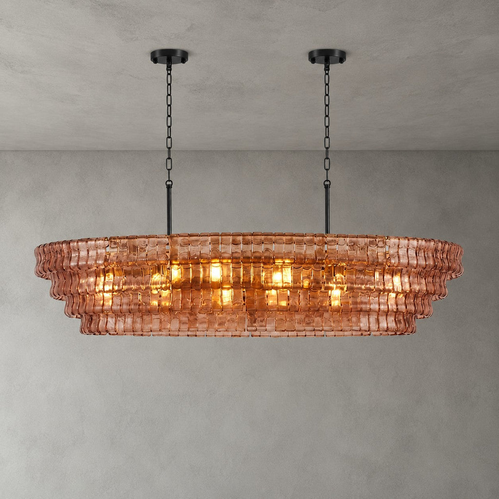 A rose-pink Clérachic chandelier with two black round canopies, its four tiers lit warm against a concrete-look wall.