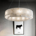 The Clérachic Rock chandelier lit above a framed print on a pale concrete wall.