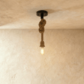 Clérachic single pendant on a thick natural hemp rope with a loose overhand knot, a black ceiling plate and a filament bulb.