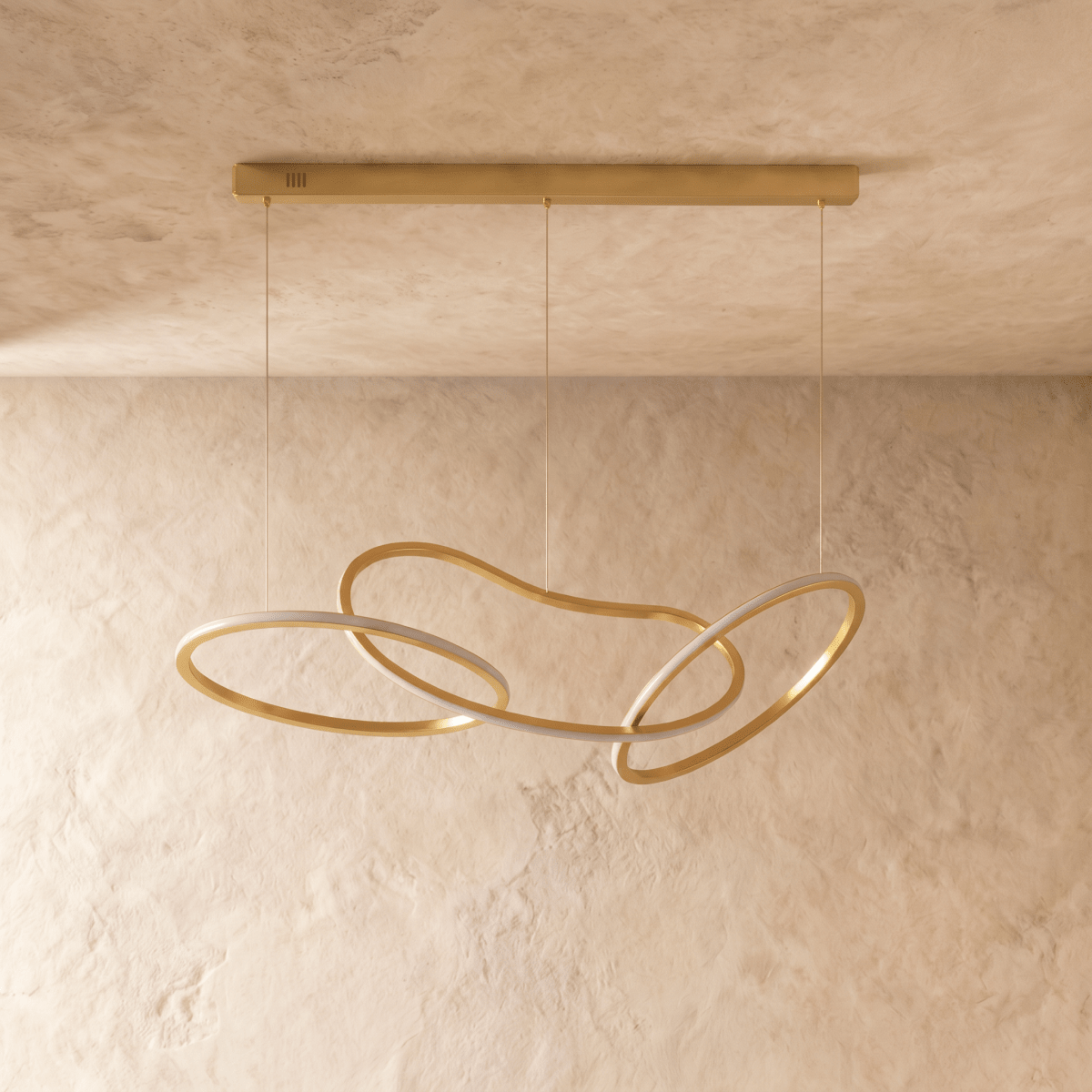 Clérachic chandelier's brushed gold rings interlock in a loose knot, suspended from a slim ceiling bar on three cables.