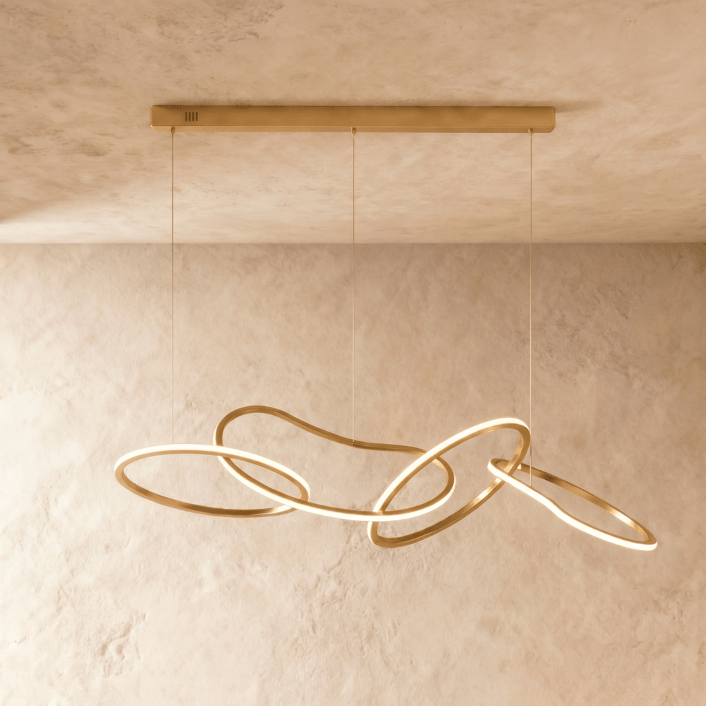 Clérachic chandelier viewed from the side, its sculptural gold loops overlapping in a continuous glowing line.