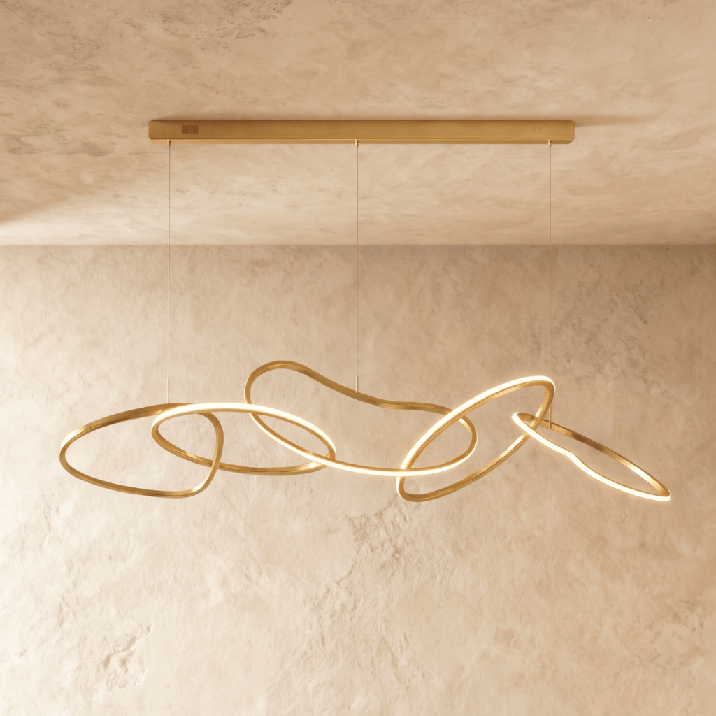 Clérachic chandelier photographed head-on, warm light tracing each brushed gold ring against a stone-toned backdrop.