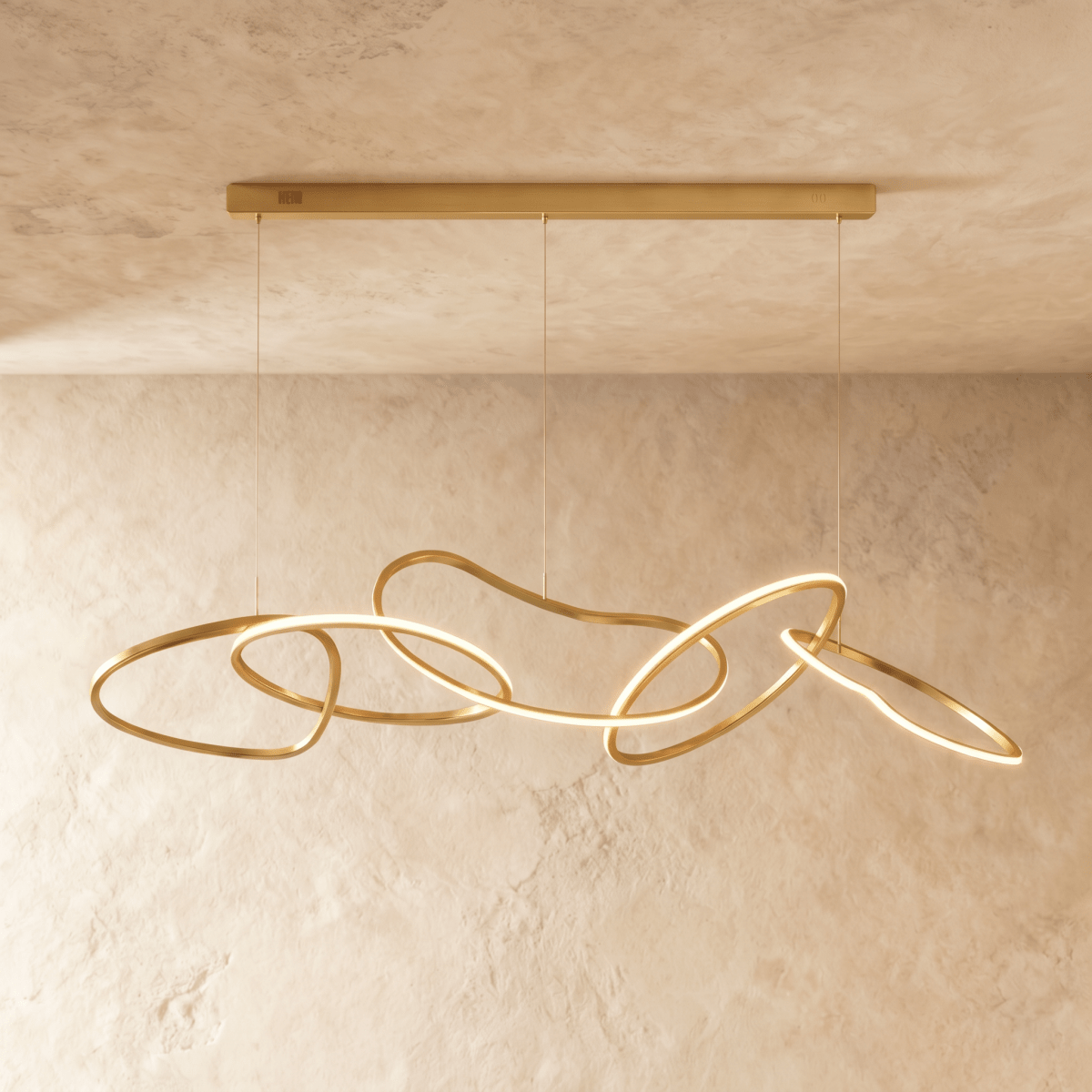 Clérachic chandelier photographed head-on, warm light tracing each brushed gold ring against a stone-toned backdrop.