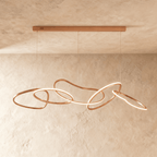 Clérachic chandelier in rose gold, shown from an angle that traces the full sweep of its looping silhouette.