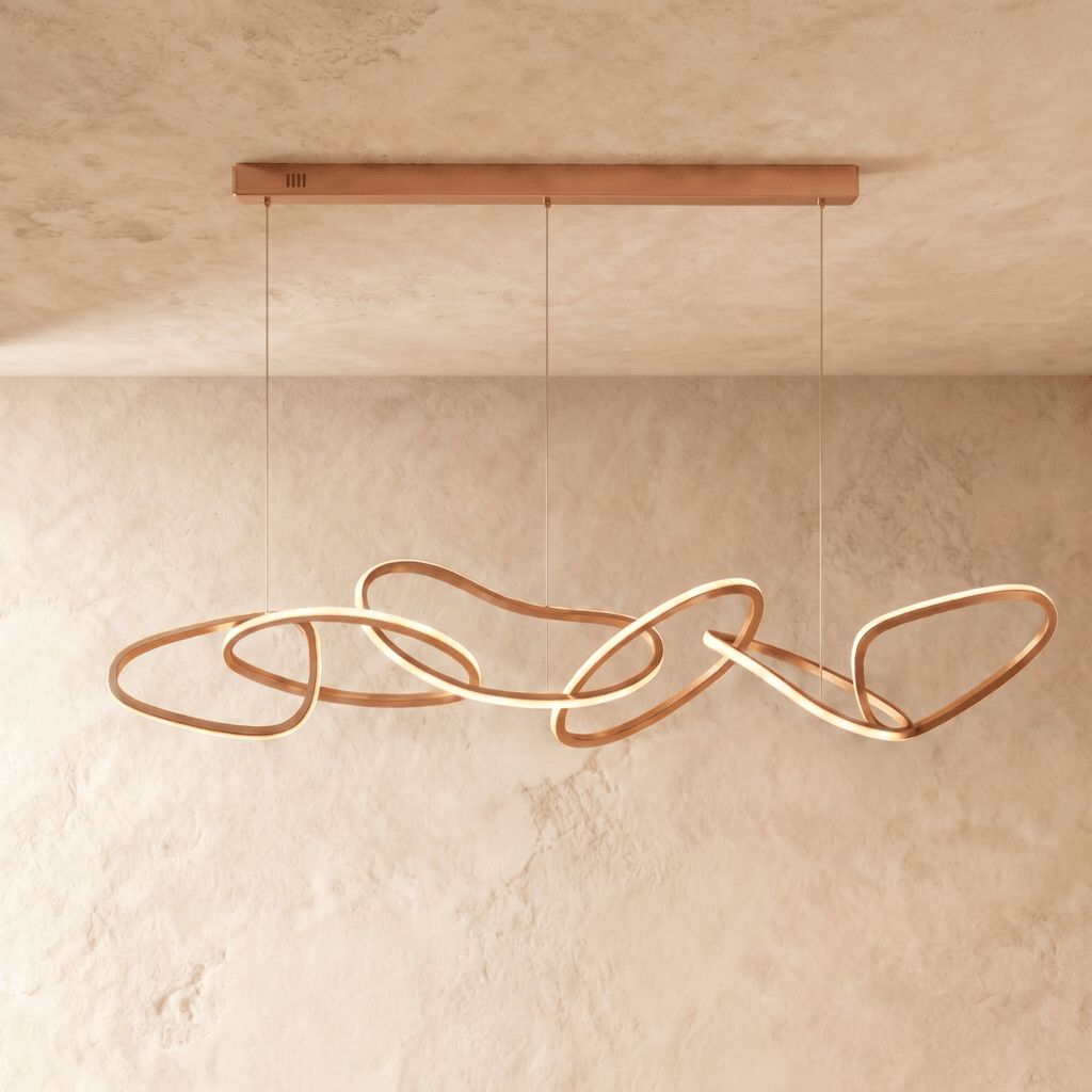 Clérachic chandelier in rose gold photographed front-on, each ring's glowing edge set against a plaster wall.