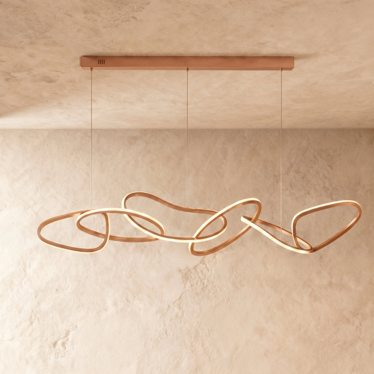 Clérachic chandelier in rose gold photographed front-on, each ring's glowing edge set against a plaster wall.