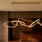 Clérachic chandelier centred above a kitchen island, its gold rings catching evening light against dark wood cabinets.