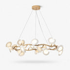 A round Clérachic chandelier with white ceramic petals on a twisting gold-toned metal ring, hung on fine wires from a round canopy.