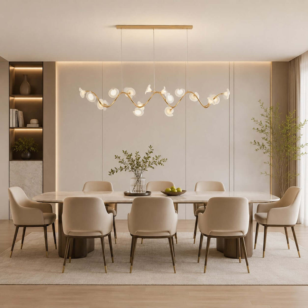 Linear Clérachic chandelier with ceramic petals on a wavy gold branch, hung above a long dining table with taupe chairs.