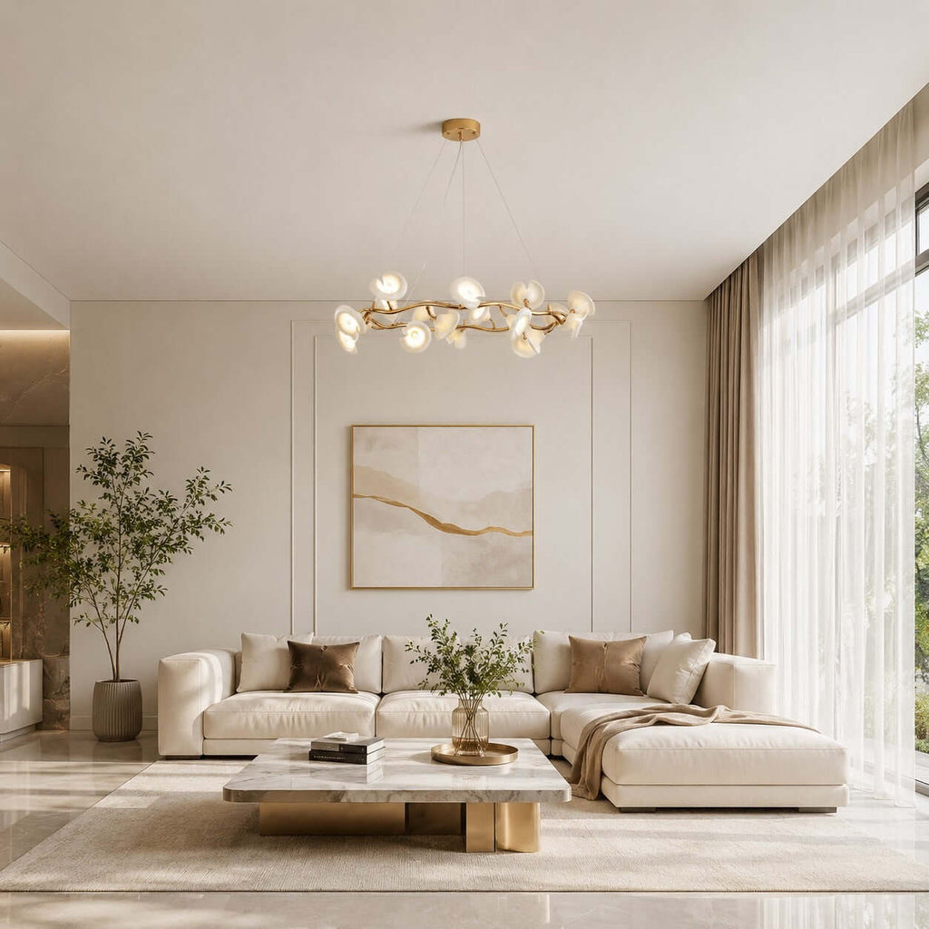 This Clérachic chandelier with gold branches and white petals hangs over a cream sectional sofa and a marble coffee table.