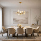 White ceramic petals on this Clérachic chandelier glow over a long dining table with quilted chairs, in front of a large soft painting.