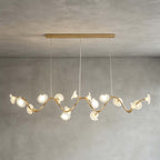 A Clérachic linear chandelier in its longer form, with petals along a wavy gold arm below a slim gold ceiling bar on grey limewash.
