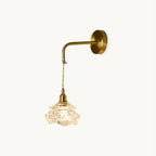 Brass wall plate and bent arm holding a twisted-cord drop to a rose-shaped glass shade, on this Clérachic wall light, on white.