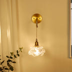 On a golden wall, this Clérachic wall light glows through its frilled glass shade, hung from a round brass backplate.