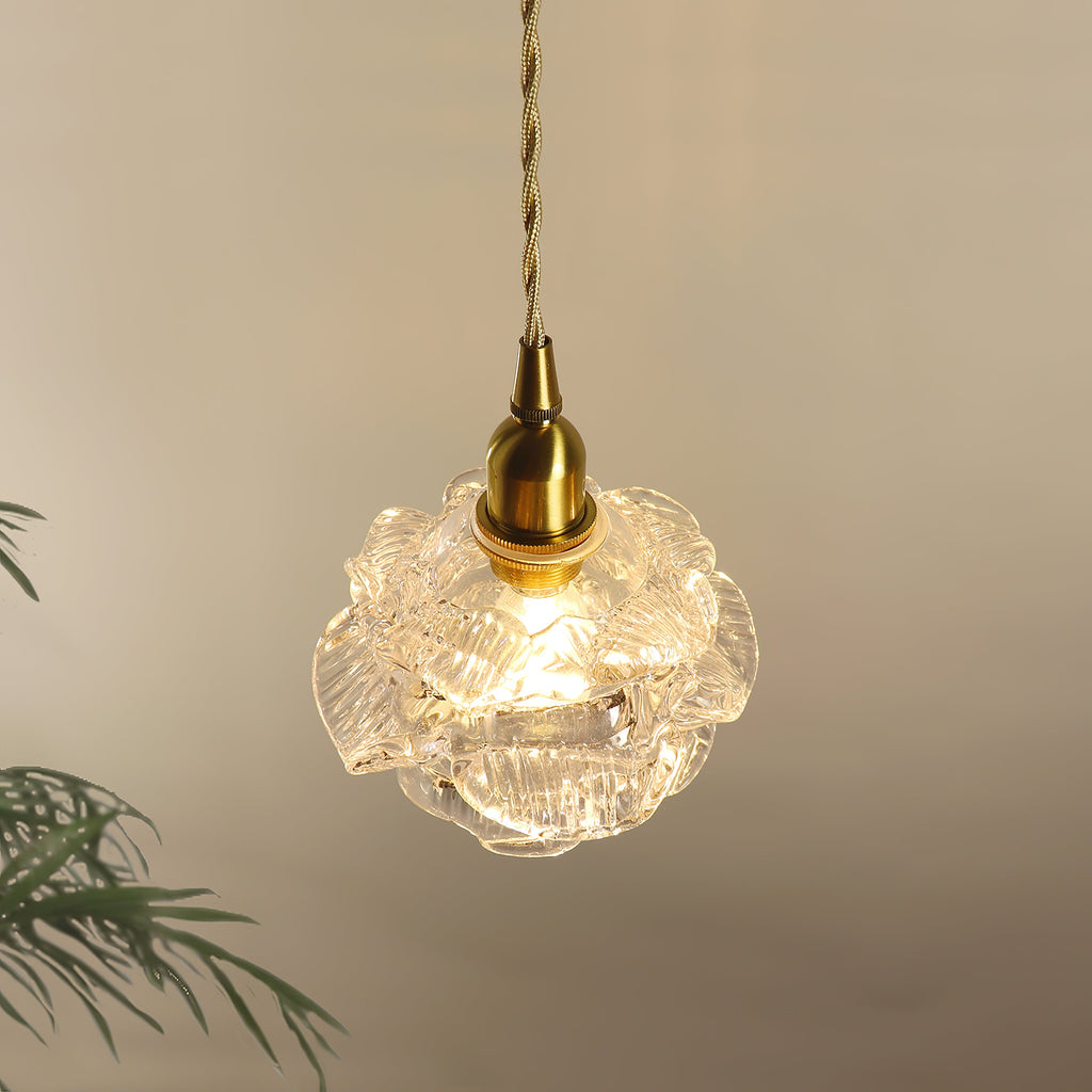 Close view of the frilled glass petals around the bulb of this Clérachic wall light, with its brass cap and twisted cord above.
