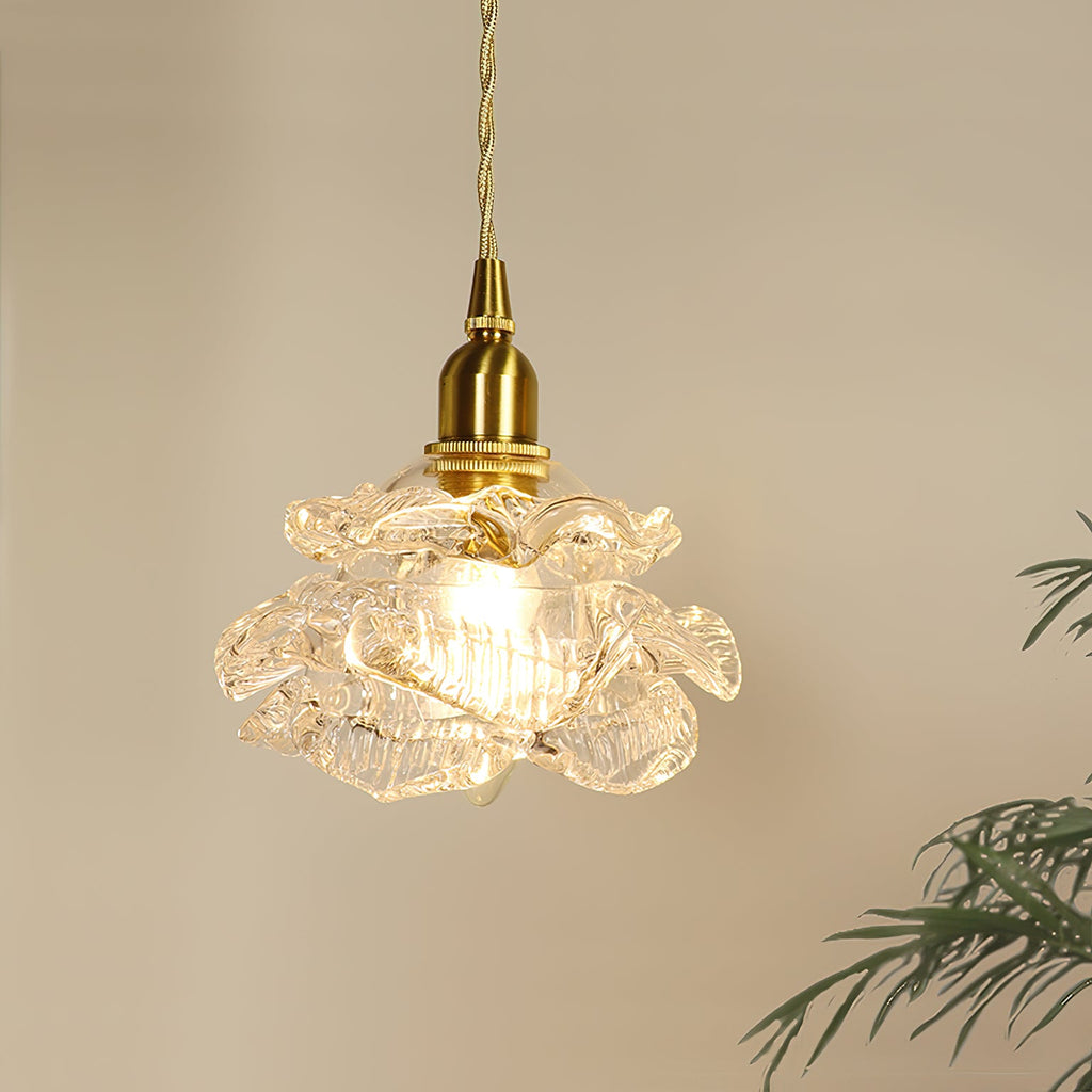 Close view of the lit, ribbed glass shade and brass lamp-holder of this Clérachic wall light, with fern leaves at the right.