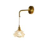 Seen on white, this Clérachic wall light has a round brass plate, an L-shaped arm and a glass shade shaped like a rose.
