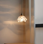 Soft light from the glass shade of this Clérachic wall light throws ripples of gold across a curtain and wall.