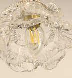 Looking up into the glass shade of this Clérachic wall light, a filament bulb sits among the ribbed, ruffled petals.