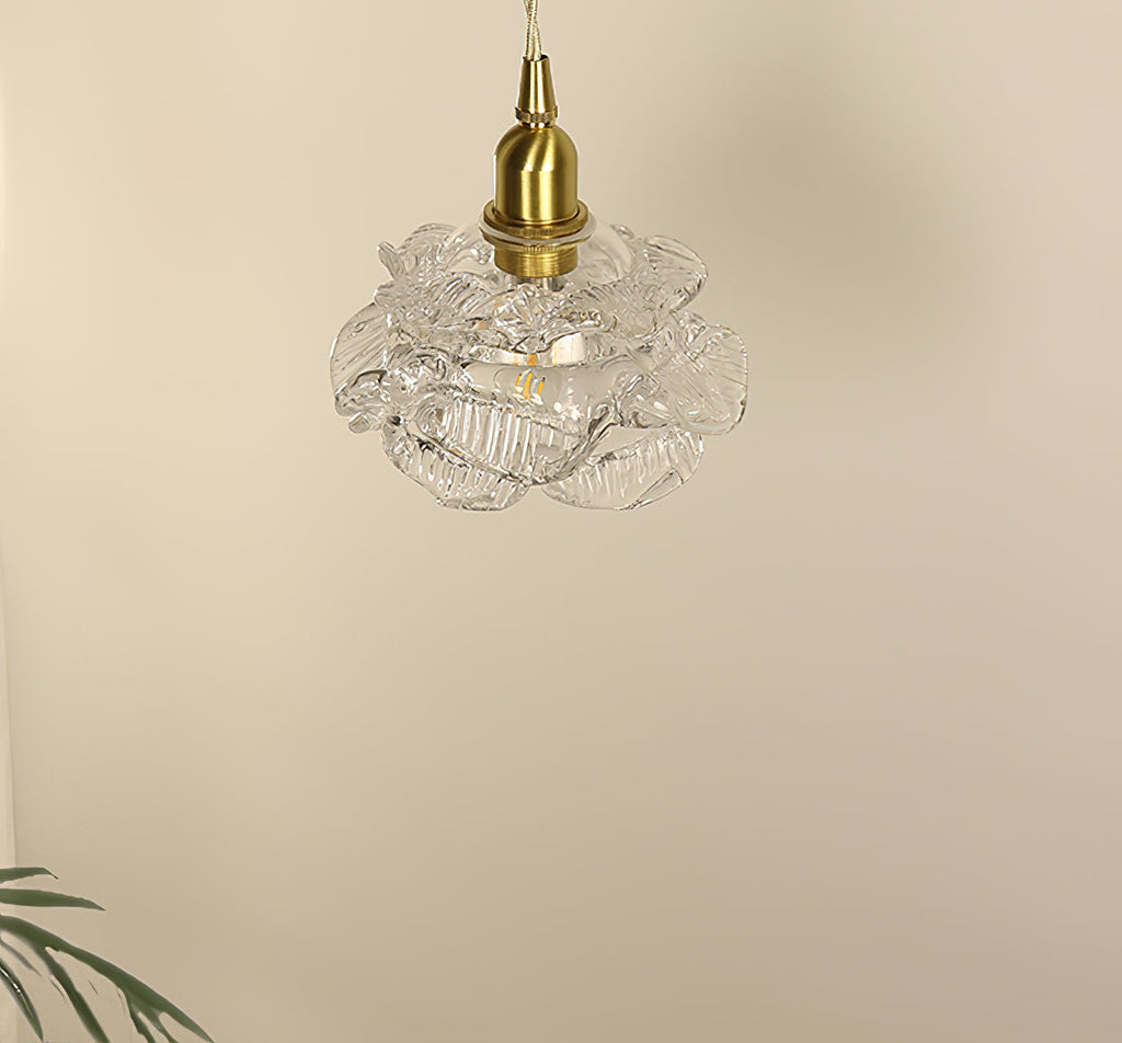 Pale, unlit rose-shaped glass shade on a brass cap and twisted cord, on this Clérachic wall light, against a cream wall.