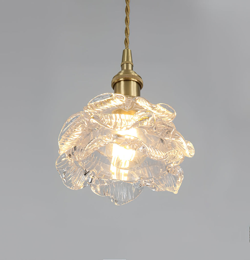 Lit from within, the layered glass petals of this Clérachic wall light shade glow beneath a brass holder on a grey backdrop.