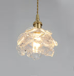 Lit from within, the layered glass petals of this Clérachic wall light shade glow beneath a brass holder on a grey backdrop.
