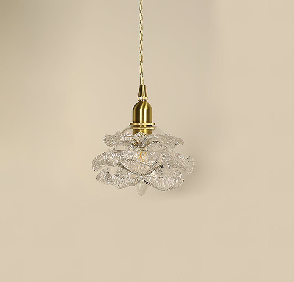 Unlit, the layered clear glass petals and brass cap of this Clérachic wall light hang against a beige wall.