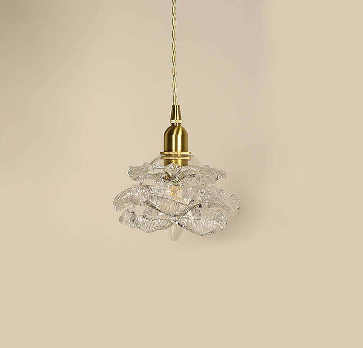 Unlit, the layered clear glass petals and brass cap of this Clérachic wall light hang against a beige wall.