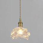 Warm light spreads through the ribbed glass shade of this Clérachic wall light on its twisted cord, against a pale grey wall.