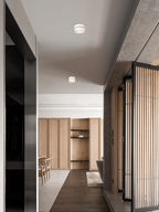 White Clérachic spotlights in a line on the ceiling of a long corridor, with a wood-panelled room and slatted screen at the far end.