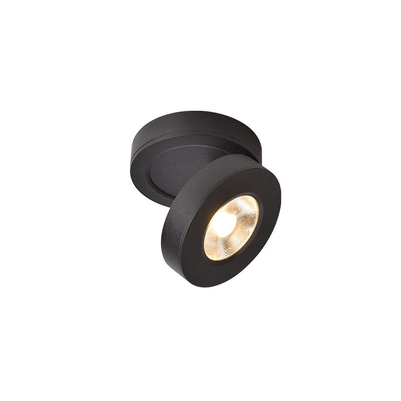 Black Clérachic spotlight on a plain white backdrop, its round head turned to face the camera, with a warm LED inside.