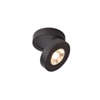 Black Clérachic spotlight on a plain white backdrop, its round head turned to face the camera, with a warm LED inside.