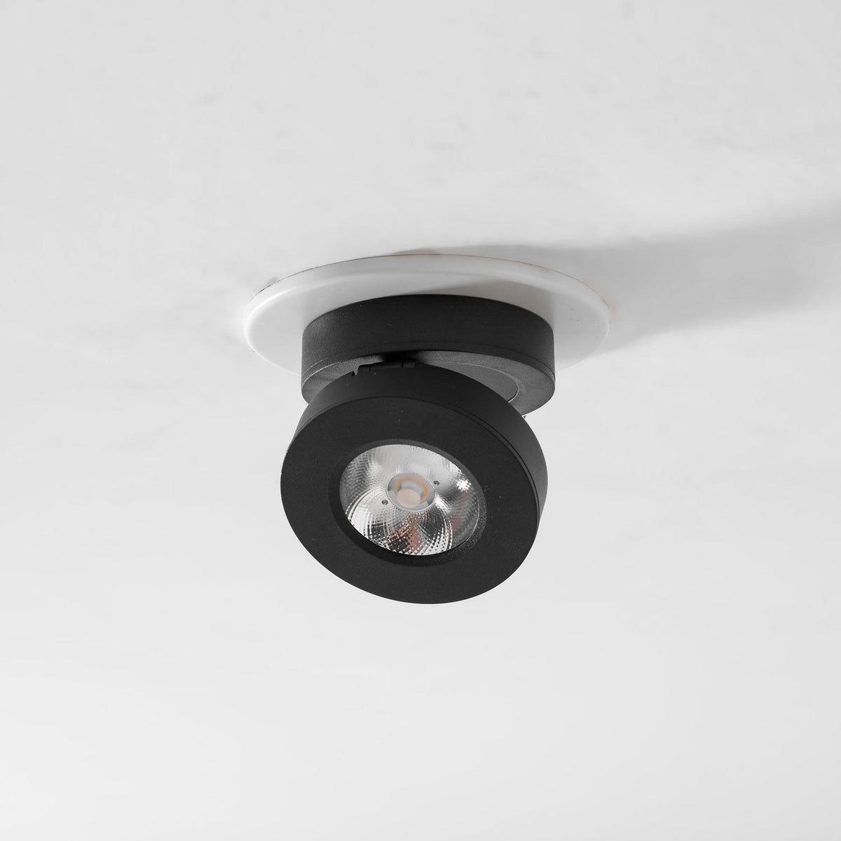 Underside view of a black Clérachic spotlight in a white ring, with a ribbed reflector and LED facing down.