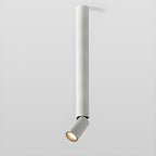 A long white Clérachic ceiling spotlight with a short angled head at the bottom, lit warm, on a pale backdrop.