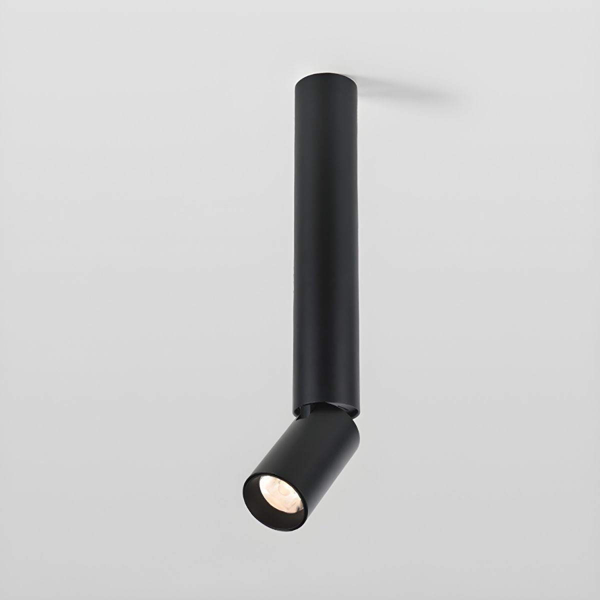A black Clérachic ceiling spotlight with a long slim pole and an angled head, shown against a pale grey backdrop.