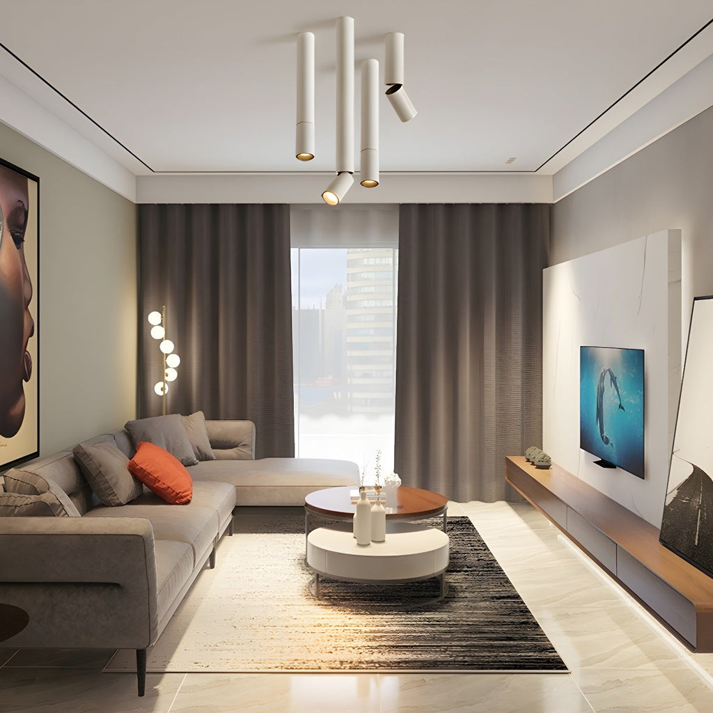 A cluster of white Clérachic spotlights in varied lengths hangs from the ceiling of a living room with a cream sofa.