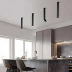 Black Clérachic ceiling spotlights of different lengths hang over a kitchen counter, the nearest with its head turned.