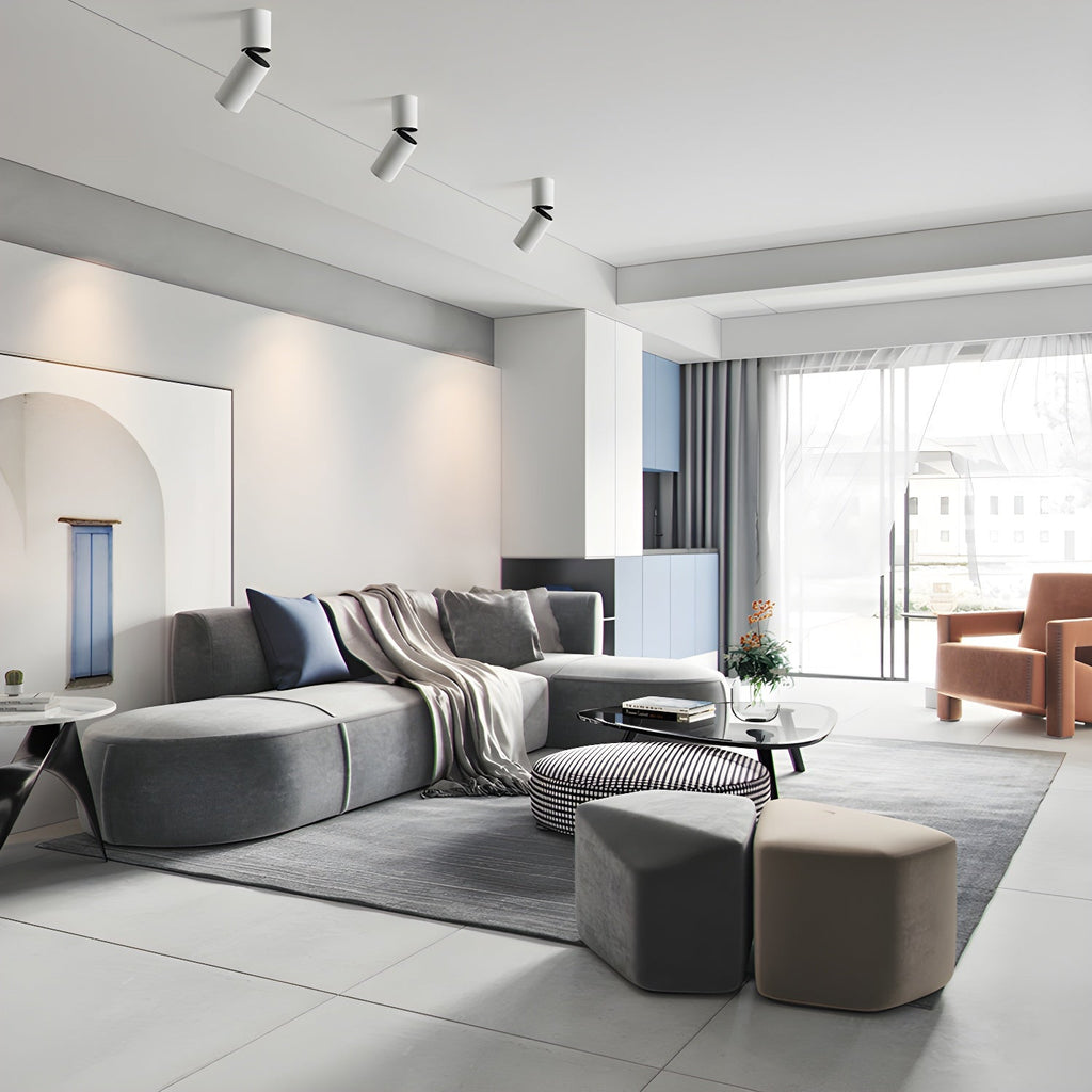 Three white Clérachic spotlights with angled heads sit high on the ceiling of a bright, open living room.